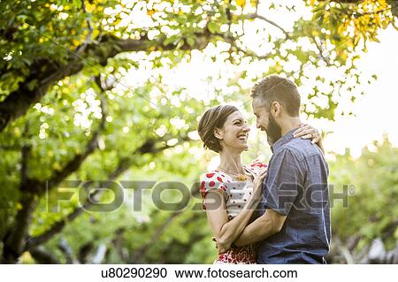 Stock Image - Couple embracing in cherry orchard. Fotosearch