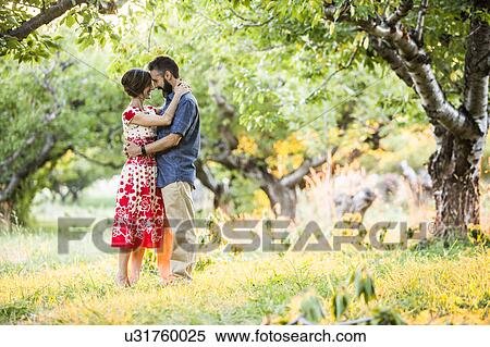 Stock Photography - Couple embracing in cherry orchard. Fotosearch