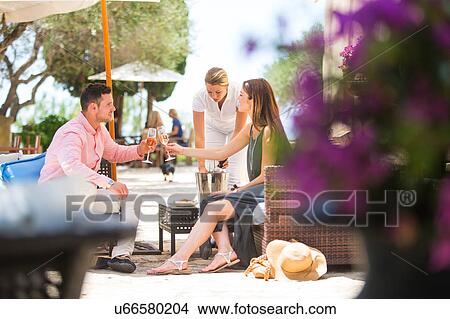 Picture - Couple making a champagne toast on boutique hotel patio, Majorca, Spain. Fotosearch