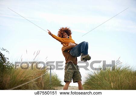 Couple playing on grassy dune View Large Photo Image Stock Image - Couple playing on grassy dune. Fotosearch