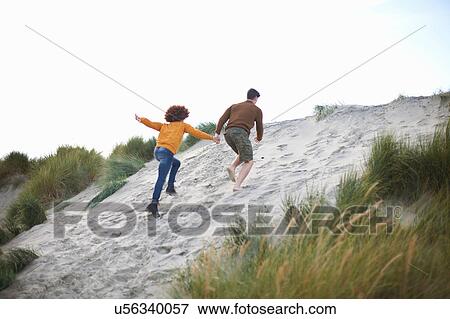 Couple racing up to top of sand dune View Large Photo Image Stock Photo - Couple racing up to top of sand dune. Fotosearch