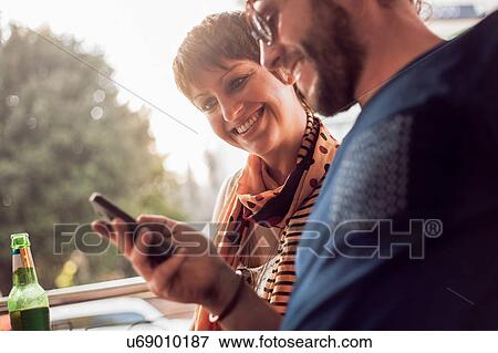 Couple reading smartphone text at sidewalk cafe View Large Photo Image Stock Photo - Couple reading smartphone text at sidewalk cafe. Fotosearch
