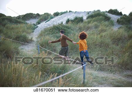 Stock Image - Couple running on grassy dune. Fotosearch
