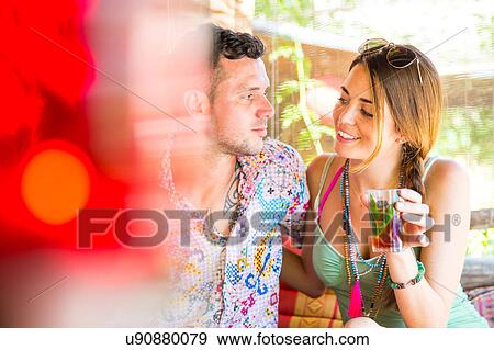 Stock Photo - Couple sitting together in pergola enjoying a drink. Fotosearch