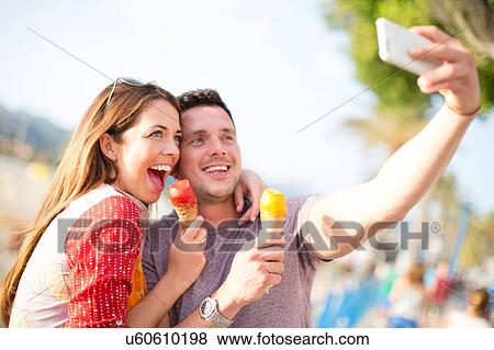 Stock Photo - Couple taking selfie eating ice cream cones, Majorca, Spain. Fotosearch