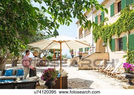 Stock Photography - Couple talking on patio at boutique hotel, Majorca, Spain. Fotosearch