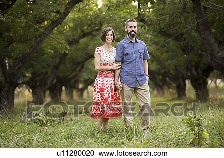 Stock Image - Couple walking in cherry orchard. Fotosearch