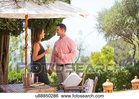Stock Photograph - Couple with champagne on boutique hotel patio, Majorca, Spain. Fotosearch