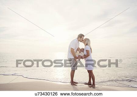 Couple with twins (2-5 months) kissing on seashore View Large Photo Image Stock Photograph - Couple with twins (2-5 months) kissing on seashore. Fotosearch