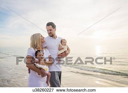 Couple with twins (2-5 months) walking along seashore View Large Photo Image Stock Photo - Couple with twins (2-5 months) walking along seashore. Fotosearch