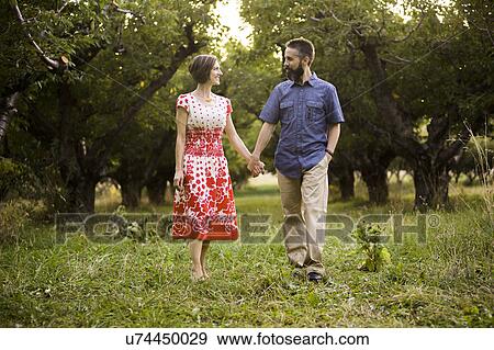 Stock Photo - Coupleholding hands in cherry orchard. Fotosearch