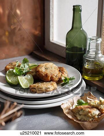 Stock Image - Crab cakes with lime slices on plate. Fotosearch