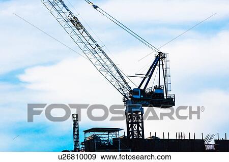 Stock Photo - Crane at construction site against sky. Fotosearch
