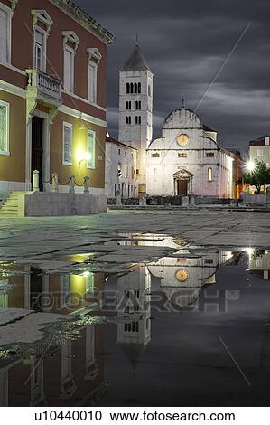 Stock Image - Croatia, Zadar, Buildings reflecting in puddle at dusk. Fotosearch