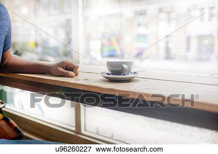 Stock Photo - Cropped shot of man at coffee shop window seat. Fotosearch