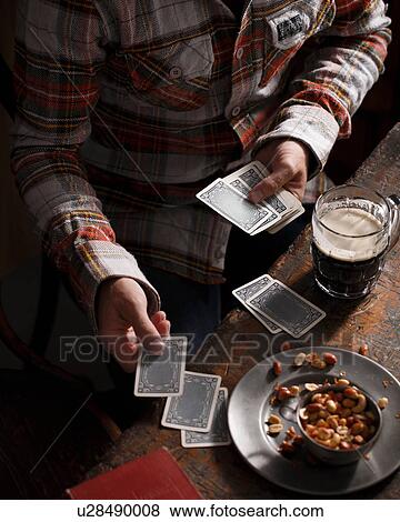 Cropped shot of man playing cards at pub table View Large Photo Image Stock Photo - Cropped shot of man playing cards at pub table. Fotosearch