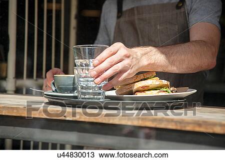 Stock Image - Cropped shot of waiter preparing order at cafe window. Fotosearch