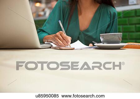 Stock Photography - Cropped shot of woman doing paperwork at cafe table. Fotosearch