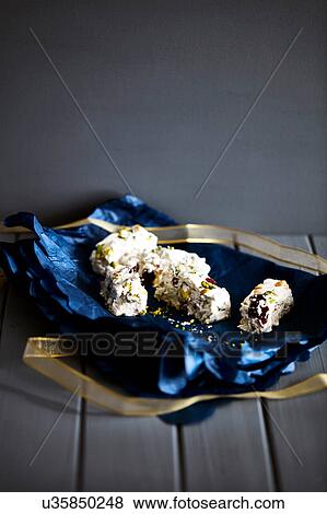 Stock Photo - Dried fruit nougat in blue christmas wrapping paper on cake stand. Fotosearch