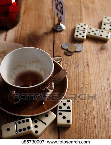 Stock Photo - Empty coffee cup and dominoes on bistro table. Fotosearch