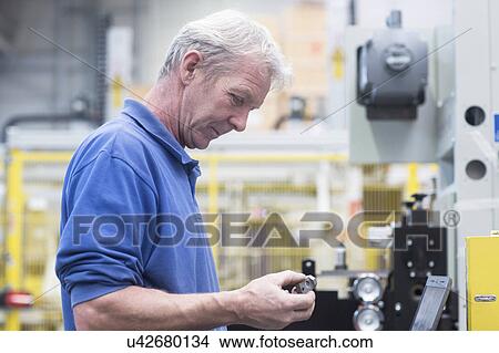 Engineer holding metal device in engineering plant View Large Photo Image Picture - Engineer holding metal device in engineering plant. Fotosearch