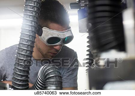 Stock Image - Engineer, wearing safety goggles, working in engineering plant. Fotosearch