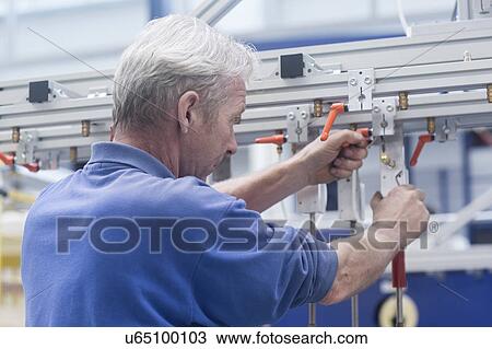 Stock Image - Engineer working at metal rail in engineering plant. Fotosearch