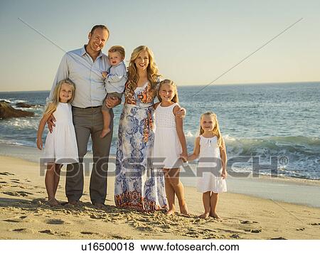 Family with children (12-17 months, 4-5, 6-7, 8-9) standing on beach with sea in background View Large Photo Image Stock Photo - Family with children (12-17 months, 4-5, 6-7, 8-9) standing on beach with sea in background. Fotosearch