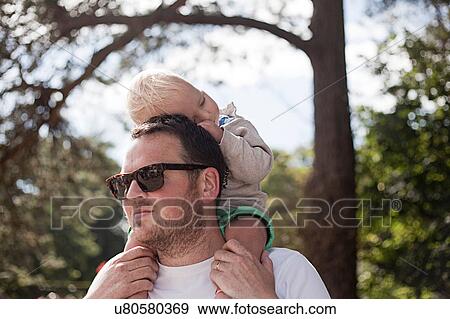 Stock Photo - Father carrying young son on shoulders. Fotosearch