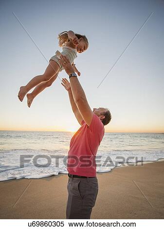 Father throwing daughter (4-5) in air on beach View Large Photo Image Stock Photography - Father throwing daughter (4-5) in air on beach. Fotosearch
