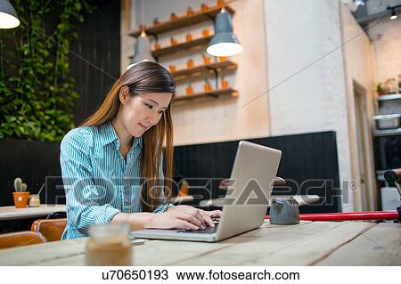 Stock Image - Female customer typing on laptop in cafe. Fotosearch