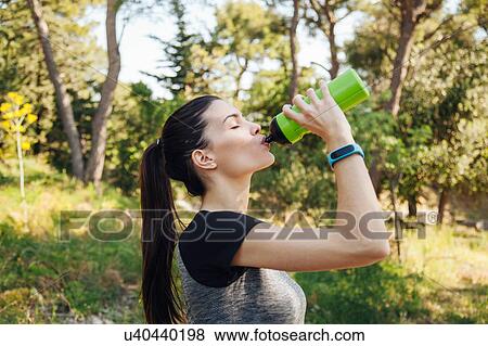 Stock Photo - Female runner drinking water bottle in park, Split, Dalmatia, Croatia. Fotosearch