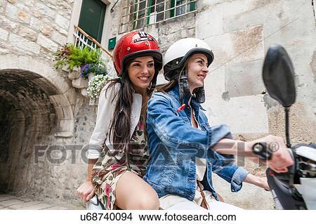 Female tourists riding moped through village, Split, Dalmatia, Croatia View Large Photo Image Picture - Female tourists riding moped through village, Split, Dalmatia, Croatia. Fotosearch