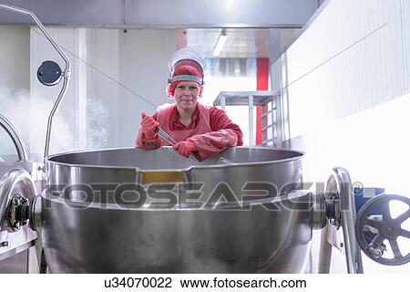 Stock Image - Female worker in cooking area of Asian food factory. Fotosearch