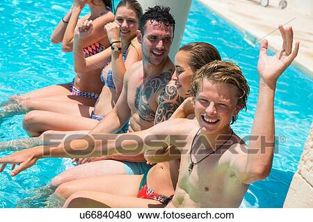 Stock Image - Five adult friends having fun in boutique hotel swimming pool, Majorca, Spain. Fotosearch