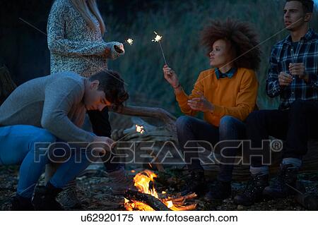 Four young adult friends playing with sparklers by campfire on beach at dusk View Large Photo Image Stock Photography - Four young adult friends playing with sparklers by campfire on beach at dusk. Fotosearch