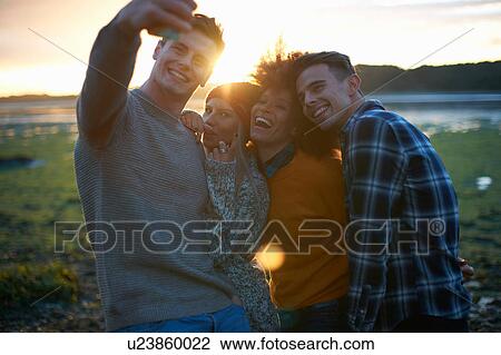 Four young adults taking smartphone selfie at seaside sunset View Large Photo Image Stock Image - Four young adults taking smartphone selfie at seaside sunset. Fotosearch
