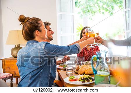 Friends dining together, making a toast View Large Photo Image Stock Image - Friends dining together, making a toast. Fotosearch
