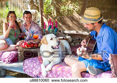 Stock Image - Friends in pergola playing guitar. Fotosearch