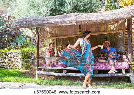 Stock Photograph - Friends in pergola playing guitar, dancing. Fotosearch