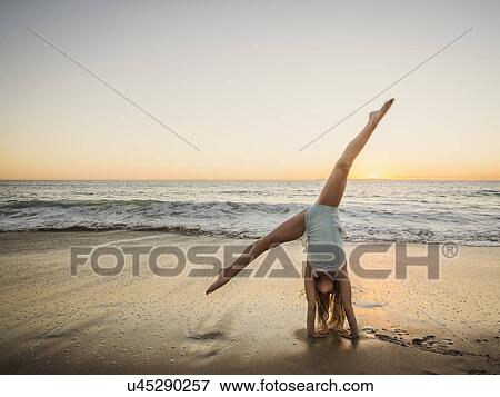 Stock Photo - Girl (8-9) doing cartwheel on beach. Fotosearch