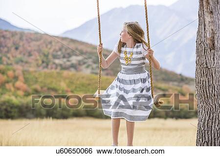 Stock Photograph - Girl (8-9) sitting on swing. Fotosearch
