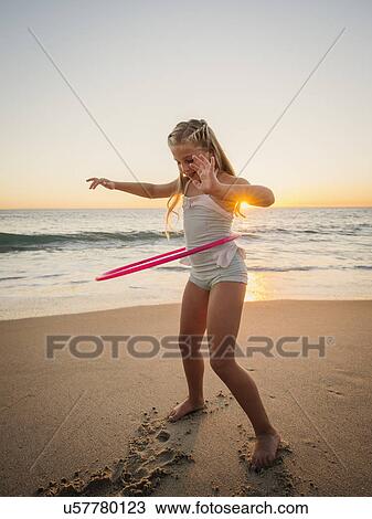 Girl (8-9) spinning plastic hoop on beach View Large Photo Image Stock Image - Girl (8-9) spinning plastic hoop on beach. Fotosearch