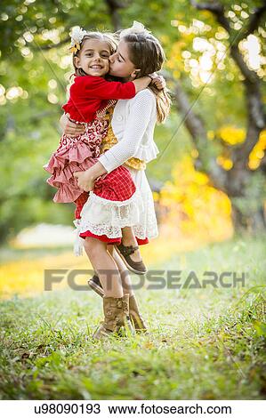 Girl holding and kissing sister in cherry orchard View Large Photo Image Stock Image - Girl holding and kissing sister in cherry orchard. Fotosearch