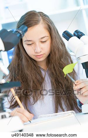 Stock Photo - Girl holding green leaf and making notes. Fotosearch