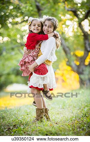 Picture - Girl holding sister in cherry orchard. Fotosearch