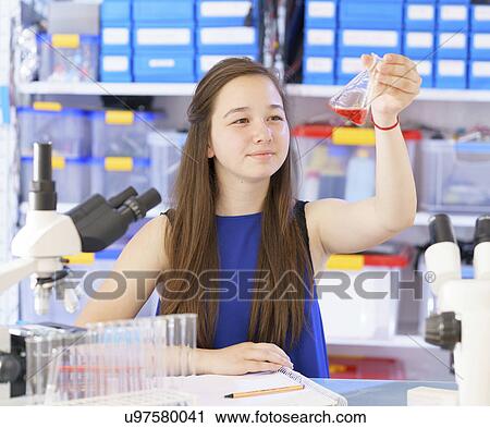 Stock Image - Girl looking at chemical in flask. Fotosearch