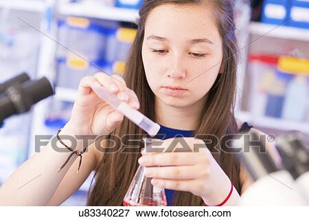 Stock Photo - Girl pouring liquid into chemical flask. Fotosearch