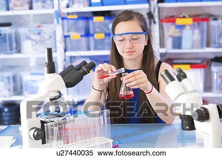 Stock Photography - Girl pouring liquid into chemical flask. Fotosearch