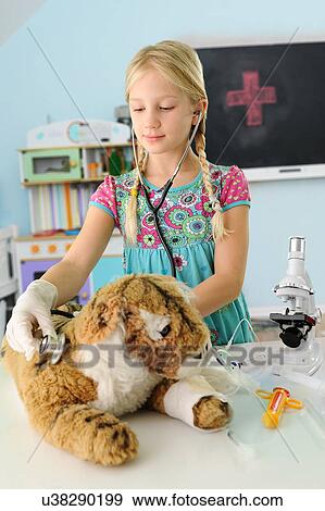 Stock Photo - Girl pretending to be vet examining toy tiger using stethoscope. Fotosearch